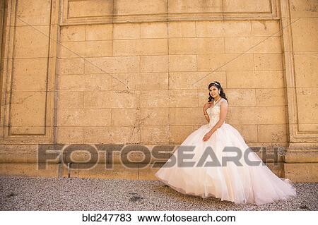 Smiling Hispanic girl wearing gown near wall View Large Photo Image Stock Image - Smiling Hispanic girl wearing gown near wall. Fotosearch