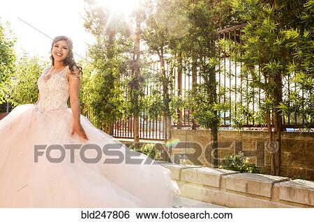 Stock Photograph - Smiling Hispanic girls wearing gown in park. Fotosearch