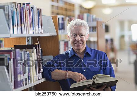 Smiling Hispanic man holding book in library View Large Photo Image Stock Image - Smiling Hispanic man holding book in library. Fotosearch