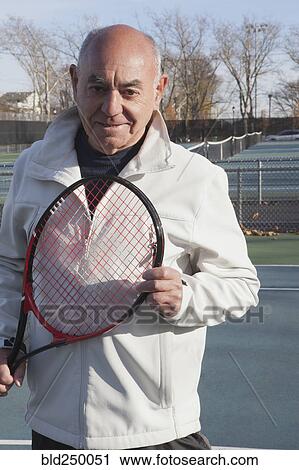 Smiling Hispanic man holding tennis racket View Large Photo Image Stock Image - Smiling Hispanic man holding tennis racket. Fotosearch
