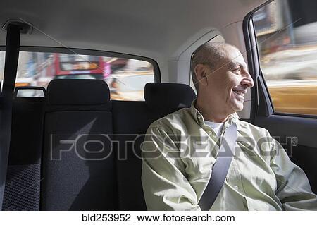 Stock Image - Smiling Hispanic man riding in car. Fotosearch
