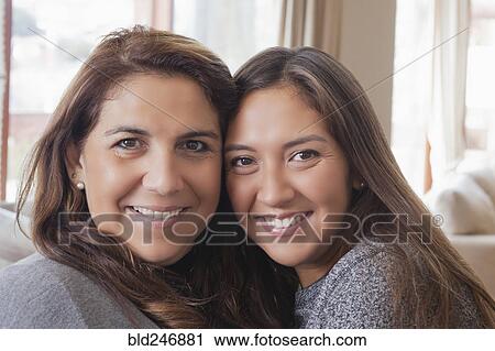 Stock Image - Smiling Hispanic mother and daughter posing cheek to cheek. Fotosearch