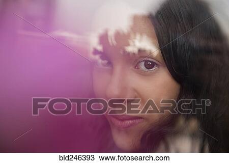 Stock Image - Smiling Hispanic woman behind window. Fotosearch