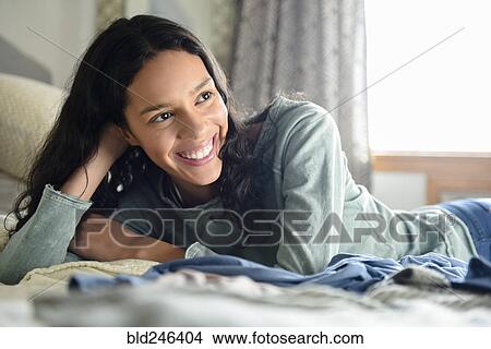 Smiling Hispanic woman laying on bed View Large Photo Image Picture - Smiling Hispanic woman laying on bed. Fotosearch