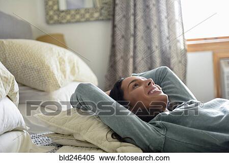 Smiling Hispanic woman laying on bed View Large Photo Image Stock Photography - Smiling Hispanic woman laying on bed. Fotosearch