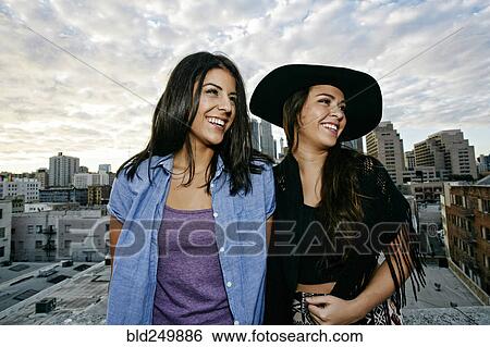 Stock Photograph - Smiling Hispanic women on urban rooftop. Fotosearch