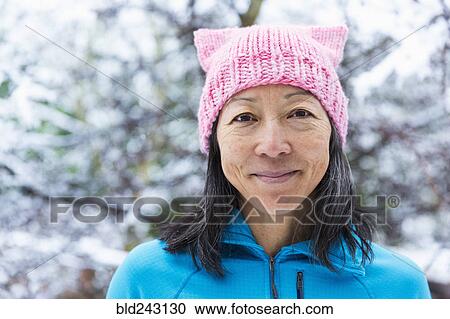 Stock Image - Smiling Japanese woman wearing pink hat with ears. Fotosearch