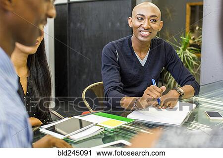 Smiling man with notebook in meeting View Large Photo Image Stock Image - Smiling man with notebook in meeting. Fotosearch