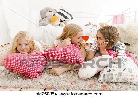 Picture - Smiling Middle Eastern sisters laying on floor talking. Fotosearch