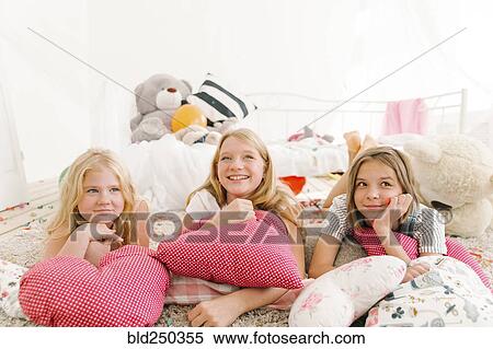 Stock Photography - Smiling Middle Eastern sisters laying on floor. Fotosearch