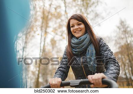 Stock Image - Smiling Middle Eastern woman pushing stroller. Fotosearch
