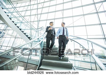 Smiling Mixed Race businessmen descending staircase and talking View Large Photo Image Stock Photograph - Smiling Mixed Race businessmen descending staircase and talking. Fotosearch