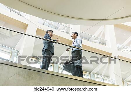 Smiling Mixed Race businessmen talking in lobby View Large Photo Image Stock Image - Smiling Mixed Race businessmen talking in lobby. Fotosearch