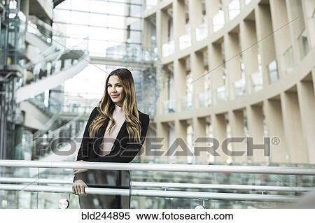 Smiling Mixed Race businesswoman leaning on railing in lobby View Large Photo Image Stock Photography - Smiling Mixed Race businesswoman leaning on railing in lobby. Fotosearch
