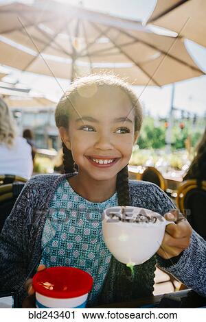 Smiling Mixed Race girl drinking from cup in restaurant View Large Photo Image Stock Image - Smiling Mixed Race girl drinking from cup in restaurant. Fotosearch