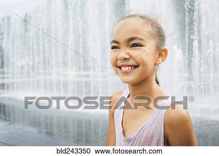 Stock Image - Smiling Mixed Race girl near fountain. Fotosearch