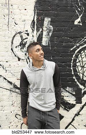 Stock Photo - Smiling Mixed Race man standing near mural on wall. Fotosearch
