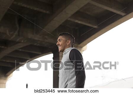 Stock Photography - Smiling Mixed Race man standing under bridge. Fotosearch