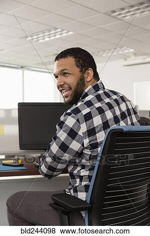 Smiling Mixed Race man using computer in office View Large Photo Image Stock Photo - Smiling Mixed Race man using computer in office. Fotosearch