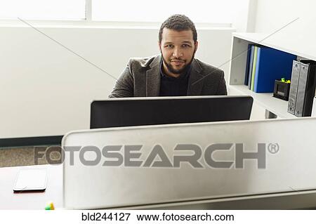 Stock Photo - Smiling Mixed Race man using computer in office. Fotosearch
