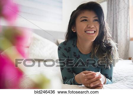 Smiling Mixed Race woman laying on bed View Large Photo Image Stock Photograph - Smiling Mixed Race woman laying on bed. Fotosearch