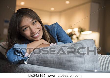 Stock Photography - Smiling Mixed Race woman leaning on sofa. Fotosearch
