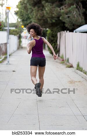 Smiling Mixed Race woman running on sidewalk View Large Photo Image Picture - Smiling Mixed Race woman running on sidewalk. Fotosearch