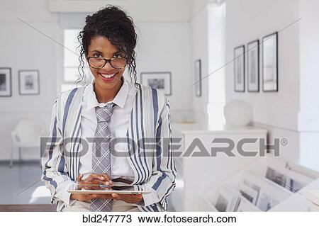 Stock Image - Smiling Mixed Race woman using digital tablet. Fotosearch