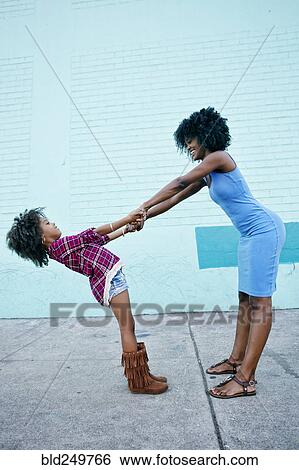 Stock Photograph - Smiling mother and daughter playing on sidewalk. Fotosearch