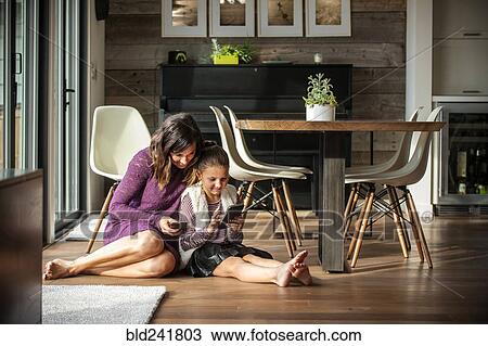 Smiling mother and daughter sitting on floor texting on cell phones View Large Photo Image Stock Image - Smiling mother and daughter sitting on floor texting on cell phones. Fotosearch