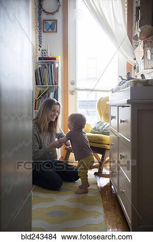 Picture - Smiling mother helping baby son walking. Fotosearch