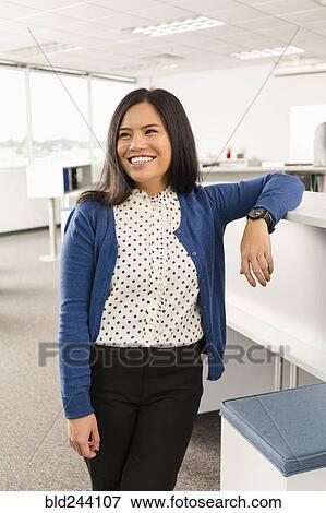 Stock Photo - Smiling Pacific Islander woman standing in office. Fotosearch