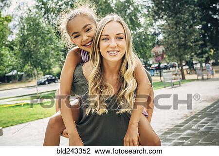 Smiling woman carrying sister piggyback View Large Photo Image Stock Image - Smiling woman carrying sister piggyback. Fotosearch