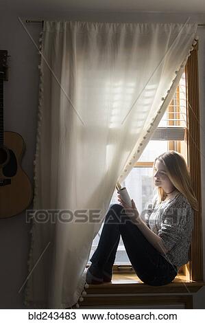Smiling woman sitting in window using digital tablet View Large Photo Image Stock Image - Smiling woman sitting in window using digital tablet. Fotosearch