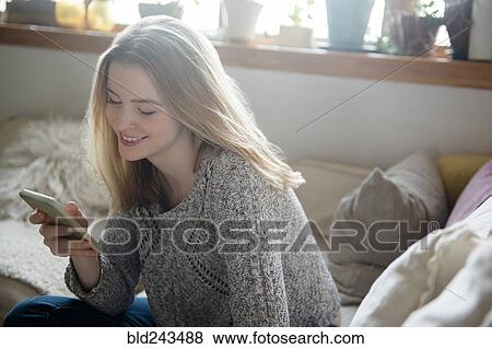 Stock Photo - Smiling woman texting on cell phone. Fotosearch