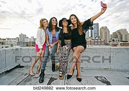 Smiling women posing for cell phone selfie on urban rooftop View Large Photo Image Stock Image - Smiling women posing for cell phone selfie on urban rooftop. Fotosearch