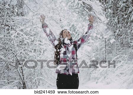 Stock Photo - Snow falling on Caucasian woman in forest. Fotosearch