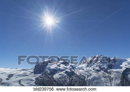 Stock Photograph - Snow on rocky landscape under sunny blue sky. Fotosearch