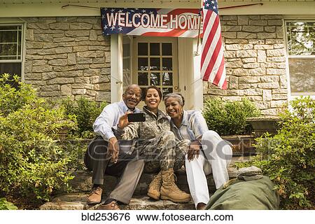 Soldier and parents sitting on front stoop posing for cell phone selfie View Large Photo Image Stock Photograph - Soldier and parents sitting on front stoop posing for cell phone selfie. Fotosearch