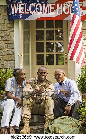 Soldier sitting on front stoop with parents and texting on cell phone View Large Photo Image Stock Photo - Soldier sitting on front stoop with parents and texting on cell phone. Fotosearch