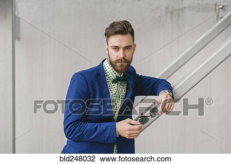 Stock Image - Stylish Middle Eastern man with beard holding sunglasses. Fotosearch