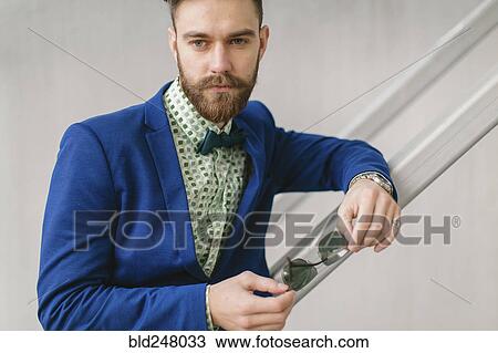 Stock Image - Stylish Middle Eastern man with beard holding sunglasses. Fotosearch