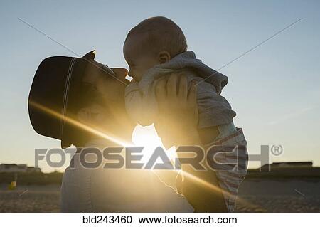 Stock Image - Sun beaming between Caucasian father and baby son. Fotosearch