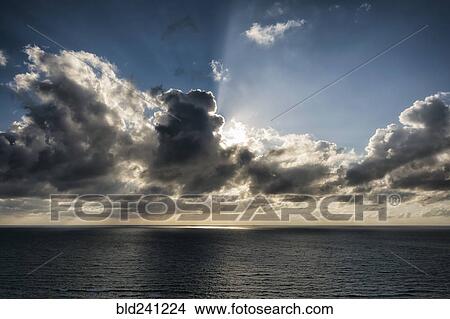 Picture - Sunbeams behind clouds over ocean. Fotosearch