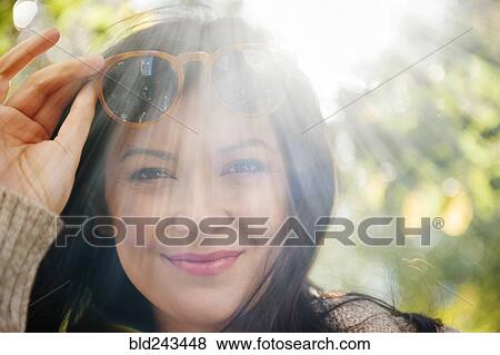 Stock Photo - Sunbeams on Caucasian woman raising sunglasses. Fotosearch