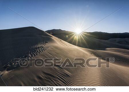 Stock Image - Sunbeams on sand dunes. Fotosearch