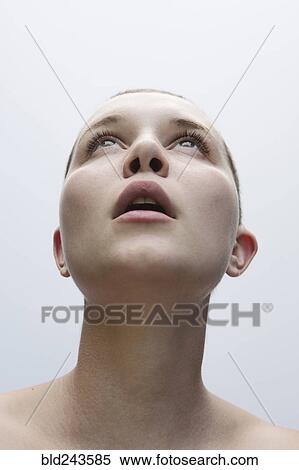 Stock Photography - Surprised Caucasian woman with shaved-head looking up. Fotosearch