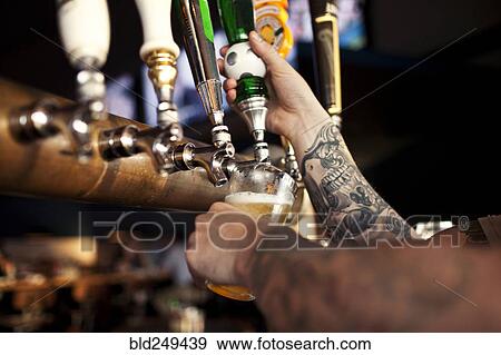 Stock Photo - Tattoos on arm of bartender pouring beer. Fotosearch