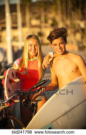 Stock Photo - Teenage boy and girl posing with surfboards and bicycles. Fotosearch