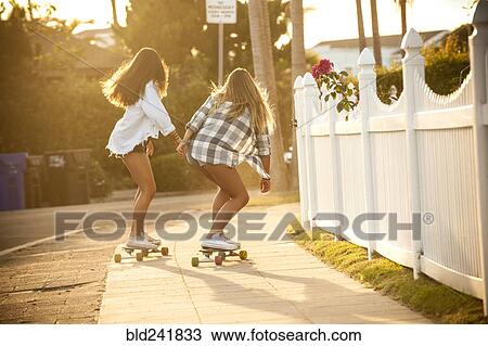 Teenage girls skateboarding on sidewalk View Large Photo Image Stock Image - Teenage girls skateboarding on sidewalk. Fotosearch